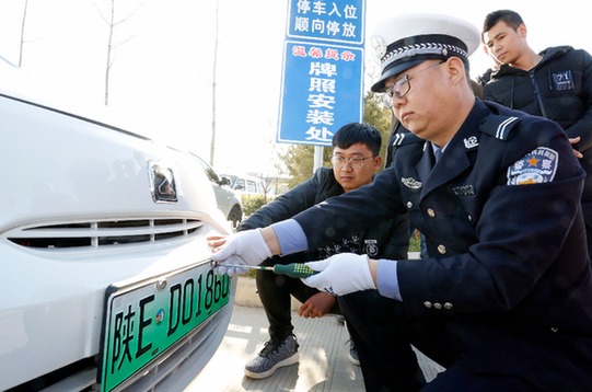 陜西民警正向消費者發放新能源汽車專用號牌 陜西民警正向消費者發放新能源汽車專用號牌